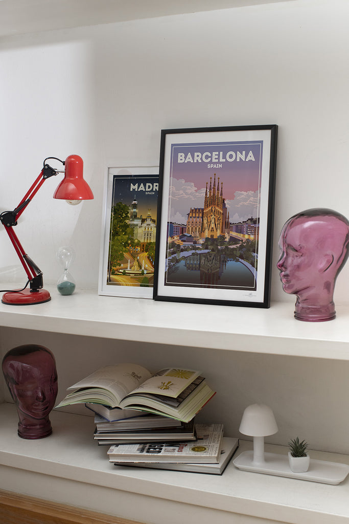 Shelf with decorative items including a red lamp, framed posters of Barcelona and Madrid, and a pink head sculpture.